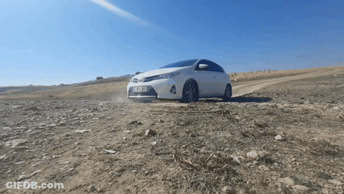 A White Car With A License Plate That Says ' Tk Xm ' On It Is Driving On A Dirt Road GIF