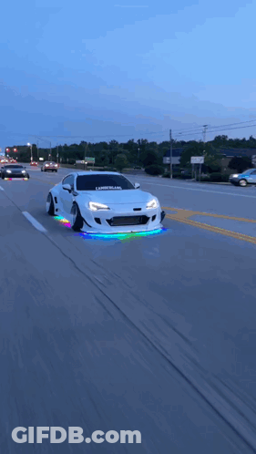 A White Car With The Word Libertyland On The Front Is Driving Down A Street GIF