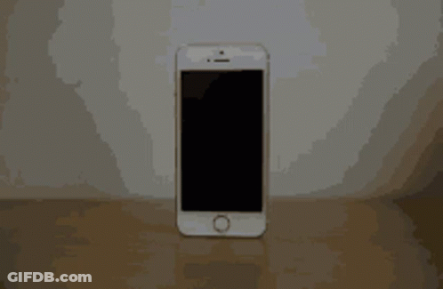 A White Cell Phone With A Black Screen Is Sitting On A Wooden Table GIF