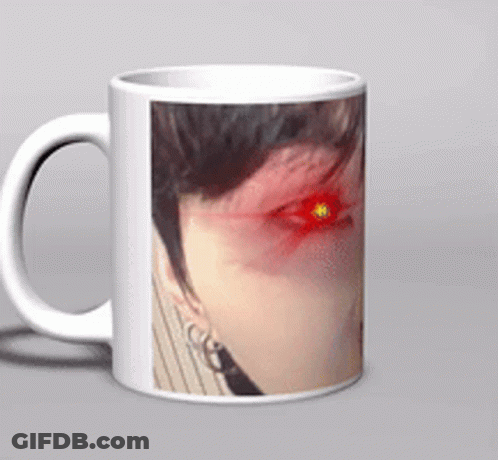 A White Coffee Mug With A Picture Of A Woman 'S Face With Red Eyes GIF