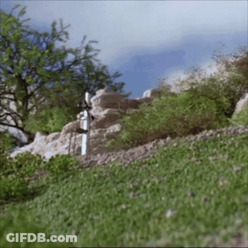 A White Cross In The Middle Of A Grassy Hill GIF
