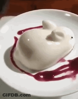 A White Dessert In The Shape Of A Cat On A White Plate With A Purple Sauce . GIF