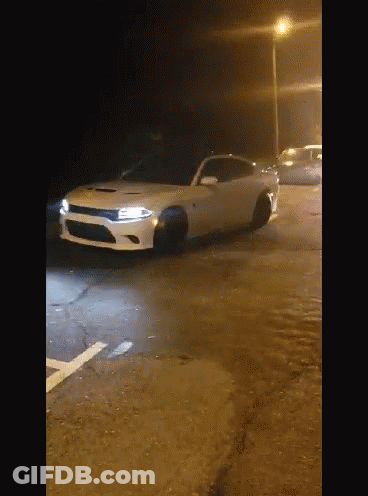 A White Dodge Charger Is Parked On The Side Of The Road At Night GIF
