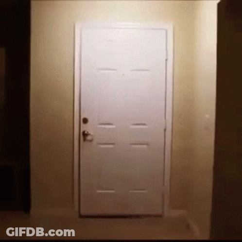 A White Door Is Open In A Hallway In A Dark Room . GIF