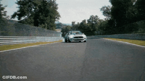 A White Ford Mustang Is Driving Down A Track GIF