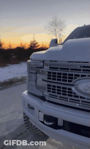 A White Ford Truck Is Parked In The Snow GIF