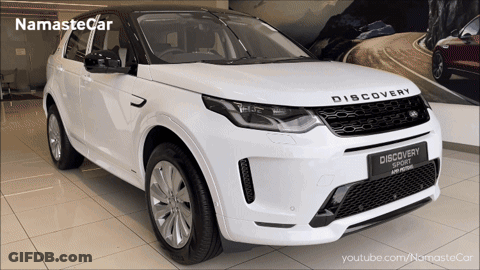 A White Land Rover Discovery Sport Is On Display In A Showroom GIF
