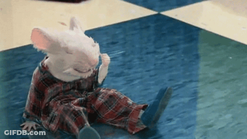 A White Mouse Is Sitting On The Floor Wearing Plaid Pajamas GIF