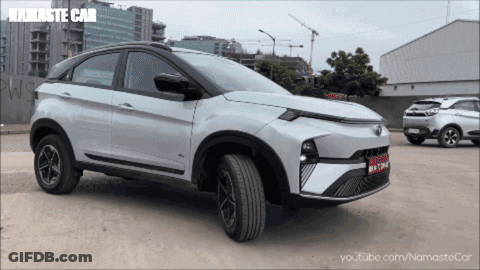 A White Namaste Car Is Parked In A Parking Lot Next To Another Car GIF