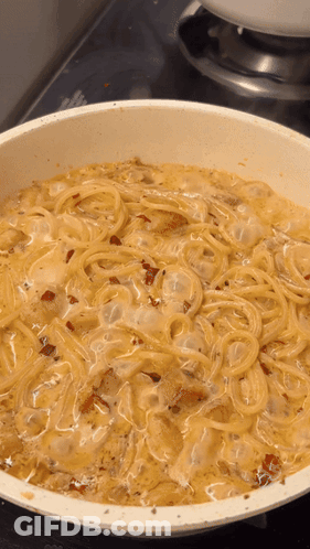 A White Pan Filled With Spaghetti And Sauce On A Stove Top GIF