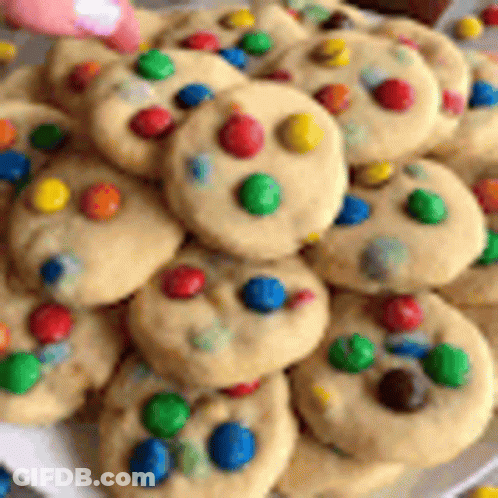 A White Plate Topped With A Bunch Of Cookies With Colored Dots On Them . GIF