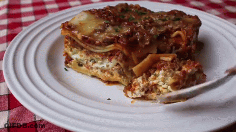 A White Plate Topped With A Slice Of Lasagna And A Fork GIF
