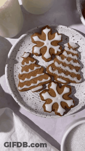 A White Plate Topped With Gingerbread Cookies In The Shapes Of A Tree Snowflake And Snowflake GIF