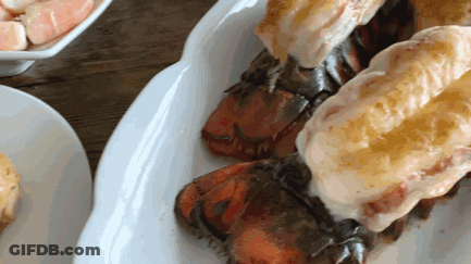 A White Plate Topped With Lobster Tails On A Table GIF