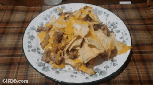 A White Plate Topped With Nachos And Cheese GIF