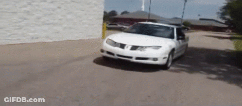 A White Pontiac Car Is Driving Down A Road GIF