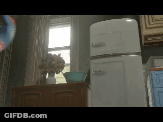 A White Refrigerator Sits In A Kitchen Next To A Vase Of Flowers GIF