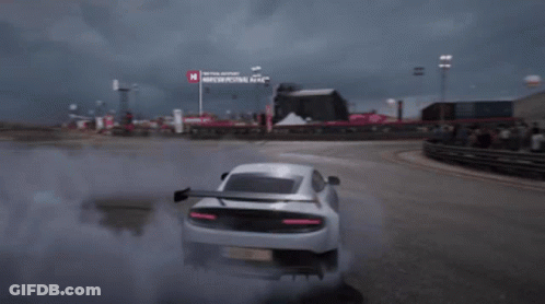 A White Sports Car Is Drifting On A Race Track With A Sign That Says Moscow Festival Next To It GIF