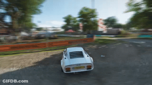 A White Sports Car Is Driving Down A Dirt Road With A Fence Behind It GIF