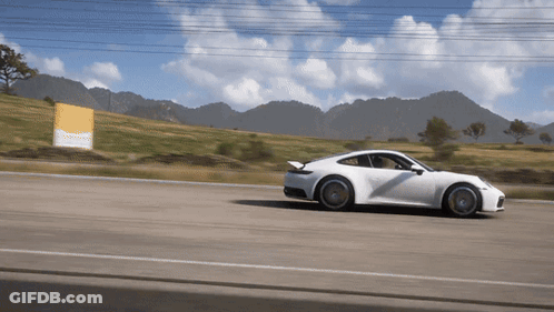 A White Sports Car Is Driving Down A Road GIF