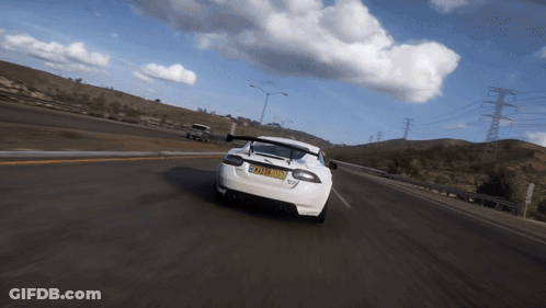 A White Sports Car Is Driving Down A Road With A License Plate That Says Tmz - Xm GIF