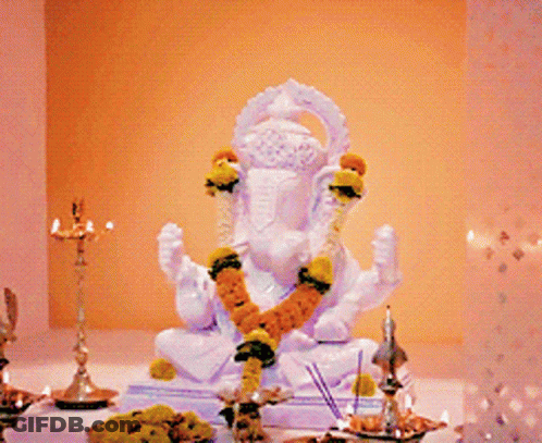 A White Statue Of A Deity With A Garland Around His Neck GIF