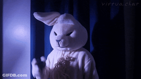 A White Stuffed Bunny Is Standing In Front Of A Blue Curtain GIF
