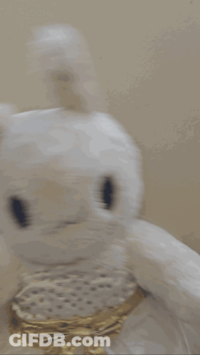 A White Stuffed Bunny With A Gold Bow On Its Neck GIF