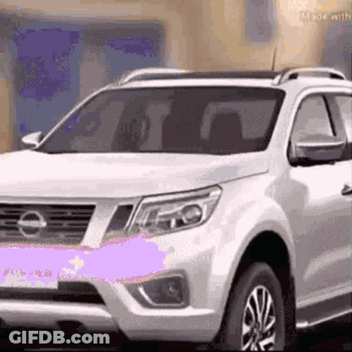 A White Suv Is Parked In Front Of A Building . GIF