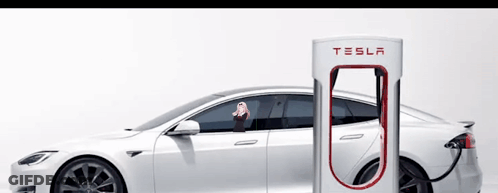 A White Tesla Is Being Charged At A Charging Station GIF