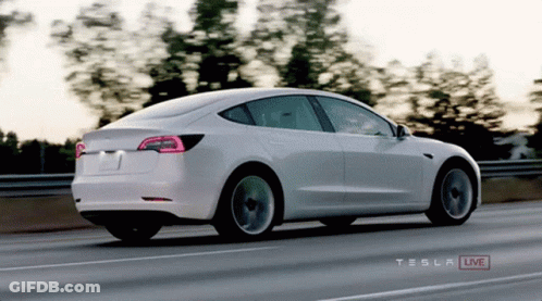 A White Tesla Is Driving Down A Highway GIF