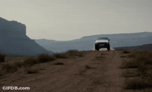 A White Truck Is Driving Down A Dirt Road GIF