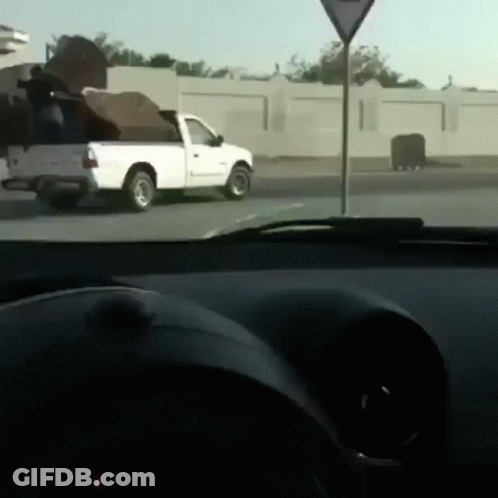 A White Truck Is Parked On The Side Of The Road Next To A Triangle Sign GIF