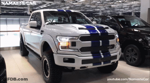 A White Truck With A Blue Stripe On The Front Is Parked Next To A Black Car GIF