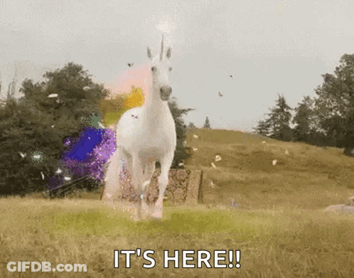 A White Unicorn Is Running In A Field With The Words It 'S Here Written Below It . GIF