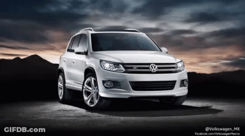 A White Volkswagen Car Is Parked In Front Of A Mountain GIF