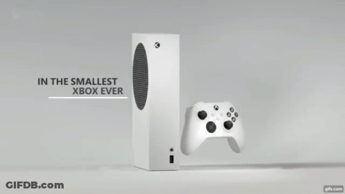 A White Xbox Controller Is Sitting Next To A Black Box On A Table . GIF