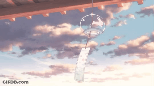 A Wind Chime With A Rabbit On It Is Hanging From A Roof With A Cloudy Sky In The Background . GIF