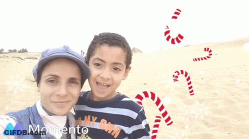 A Woman And A Boy Are Posing For A Picture With Candy Canes And Snowflakes In The Background GIF