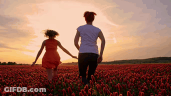 A Woman And A Girl Are Holding Hands In A Field Of Red Flowers GIF