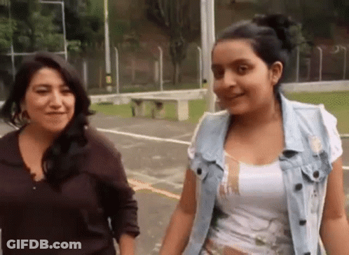 A Woman And A Girl Are Standing Next To Each Other In A Park . GIF