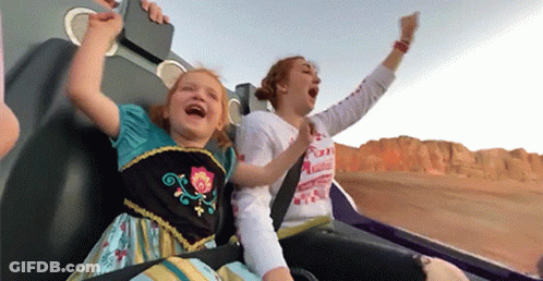 A Woman And A Little Girl Are Riding A Roller Coaster And The Little Girl Is Wearing A Frozen Dress GIF