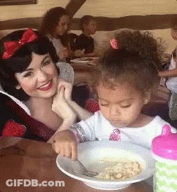 A Woman And A Little Girl Are Sitting At A Table With A Bowl Of Food In Front Of Them GIF