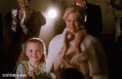 A Woman And A Little Girl Are Standing In Front Of A Crowd . GIF
