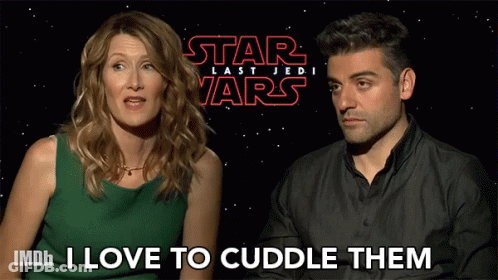 A Woman And A Man Are Sitting In Front Of A Star Wars Poster GIF