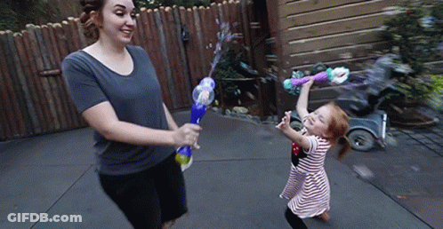 A Woman And Child Are Playing With Soap Bubbles GIF