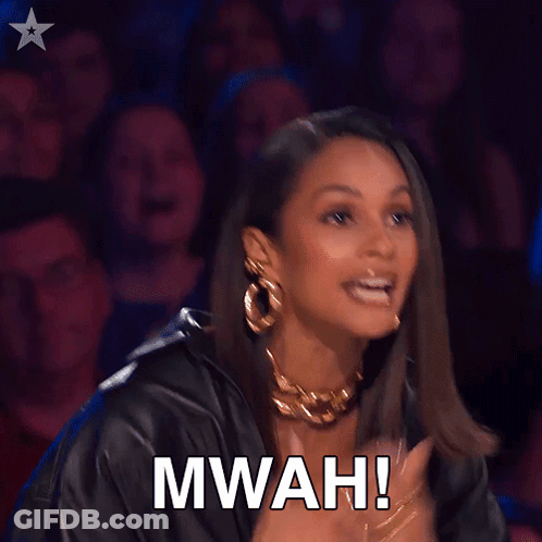 A Woman Applauds In Front Of A Crowd With The Words Mwah Written On Her Face GIF
