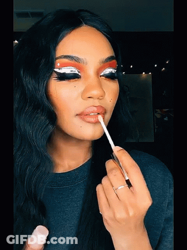A Woman Applies Lip Gloss To Her Lips With A Brush GIF