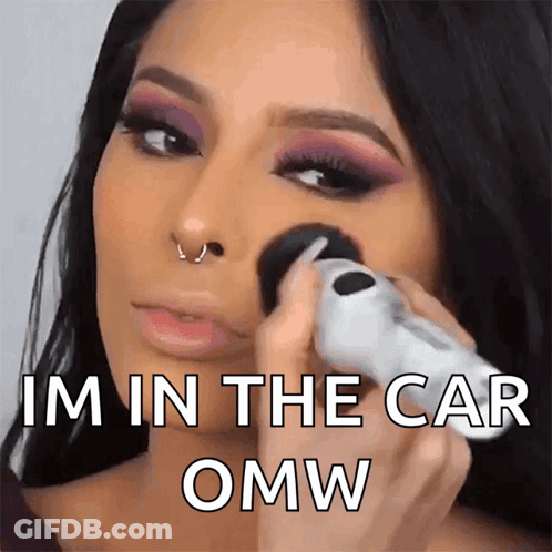 A Woman Applying Makeup With The Words Im In The Car Omw GIF