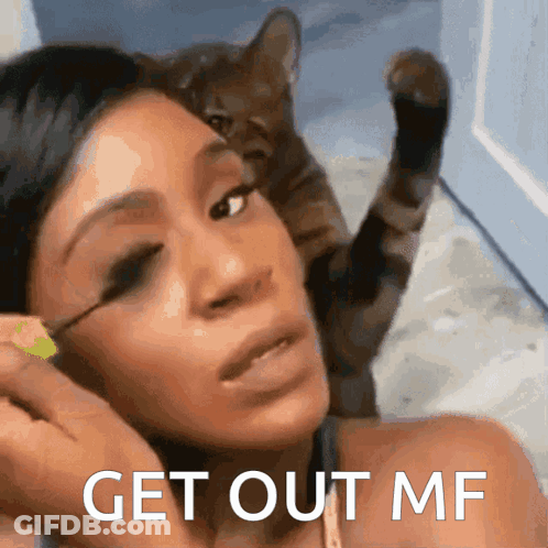 A Woman Applying Mascara With A Cat Behind Her And The Words Get Out Mf On The Bottom GIF